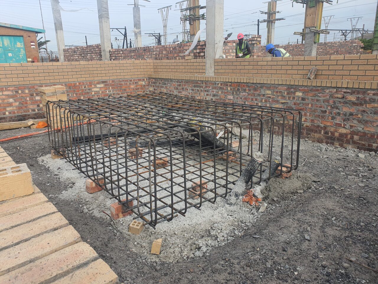 Reinforcing steel cage for substation foundation inside brick retaining walls